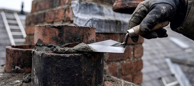 Dressing fresh mortar joints around a chimney pot in Edison